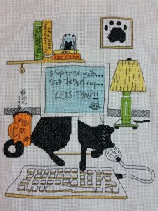 cross stitch computer cat, desk with keyboard, lamp, books