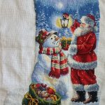 cross stitch holiday glow christmas stocking. Santa giving gift to snowman, bag of toys