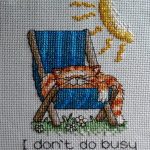 cross stitch I don't do busy with cat sleeping on chair in sunshine