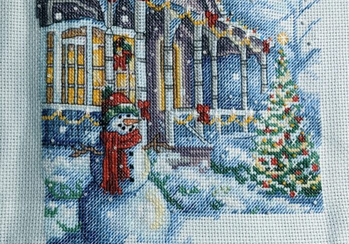 Cross stitch Christmas tradition stocking. snowman in front of house