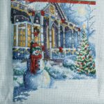 Cross stitch Christmas tradition stocking. snowman in front of house